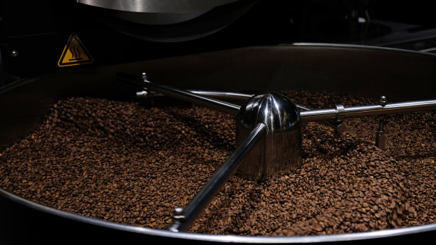 咖啡烘焙机在咖啡烘焙过程中。混合咖啡豆。烘烤的旋转冷却器专业机器和新鲜的棕色咖啡豆运动近距离黑暗照片在工厂。图片下载