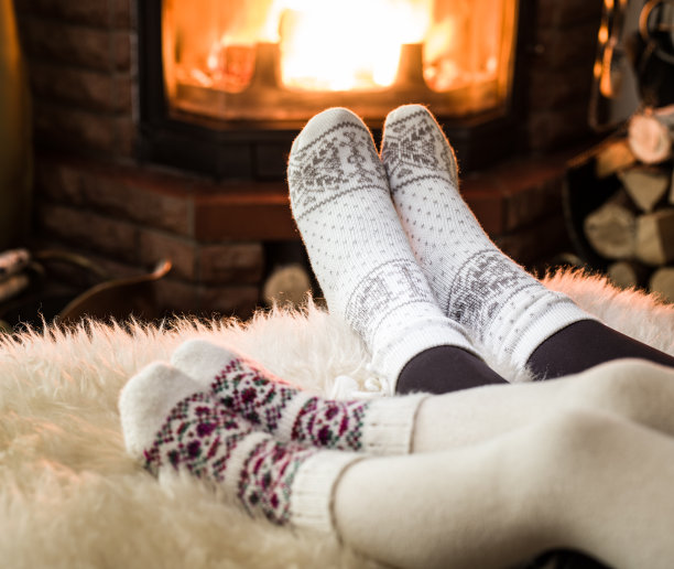 在壁炉旁取暖和放松。女人和孩子的脚在火前。图片下载