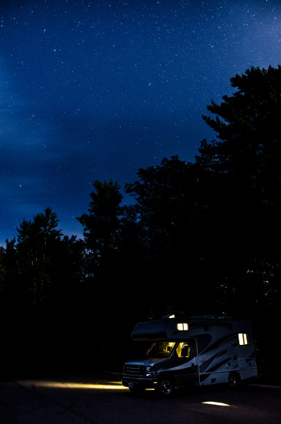 在繁星点点的夏夜，停在停车场的房车图片下载