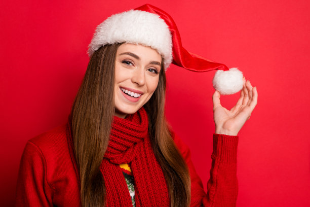 欢快快乐的正面女人手握帽子球圣诞老人孤立在红色背景上的照片图片下载