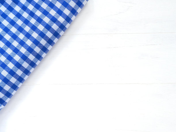 俯视图，特写的蓝色和白色格子织物或餐巾在白色的桌子背景。概念厨房用具和餐具。平铺有复制空间。图片下载