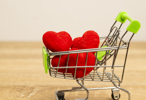 红心放在超市手推车上，棕色的桌子上，白色的背景和复制空间。图片下载