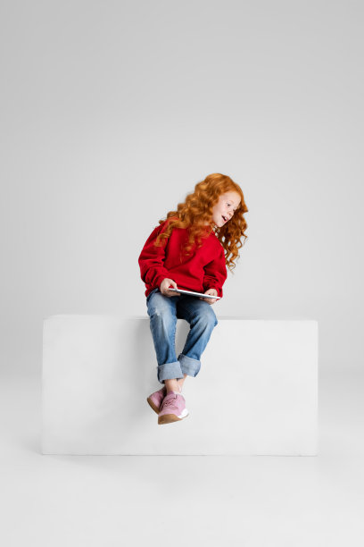 小白种人女孩的肖像，孩子与平板摆出孤立的灰色工作室背景。快乐的童年图片下载