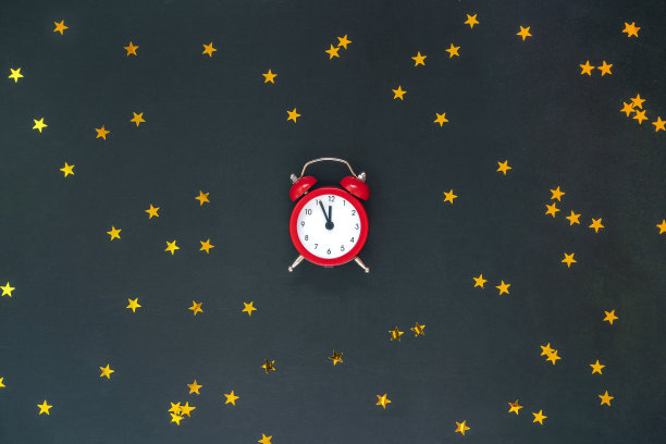 圣诞作文与红色闹钟十二和金色的星星五彩纸屑在黑色的背景。新年，圣诞佳节。图片下载