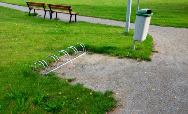 自行车轮架的灰色板金属管在草坪上呈长方形，铺在城市的花岗岩立方体、砂砾、公园小路上图片下载