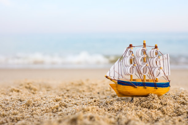 海边沙滩上的玩具船。暑假的概念图片下载