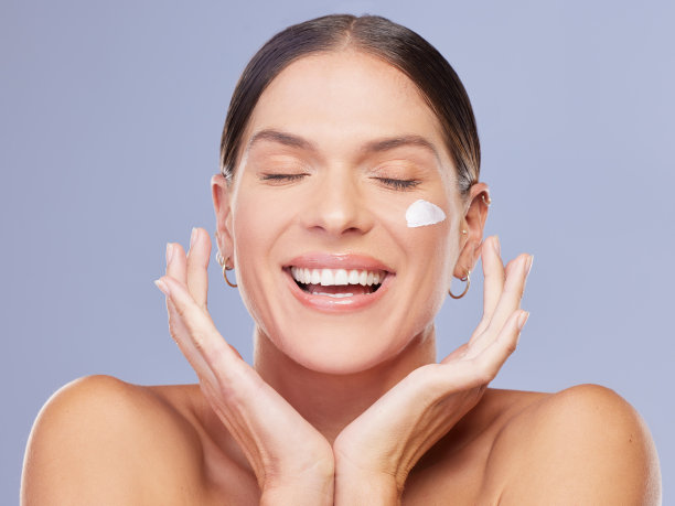 照片中一位迷人的年轻女子在紫色的背景下涂抹润肤霜图片下载