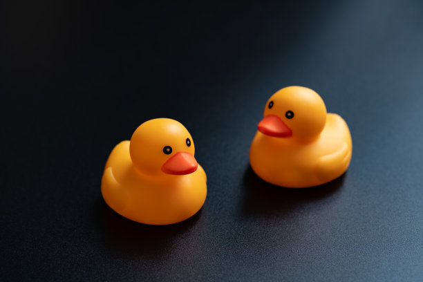 黑色背景上的黄色玩具鸭子图片下载