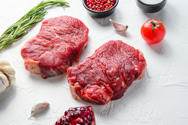 生牛排，农场牛肉，调味料，迷迭香，大蒜，石榴石。白色纹理背景。侧视图。图片下载