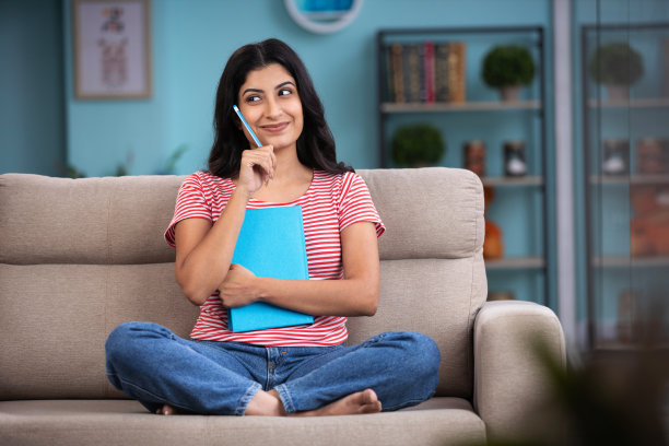 一个女人在家里的沙发上看书。库存图片图片下载