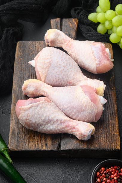 有机鸡腿配香料和大蒜，放在木制砧板上，黑色的石头背景上图片下载