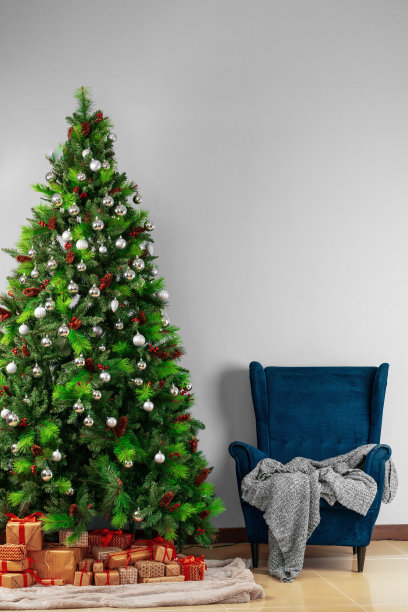 假期内。漂亮的装饰圣诞树与蓝色扶手椅图片下载