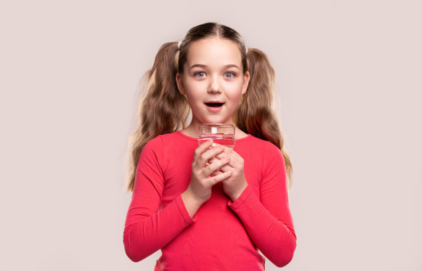 惊奇的孩子在工作室拿着一杯水图片下载