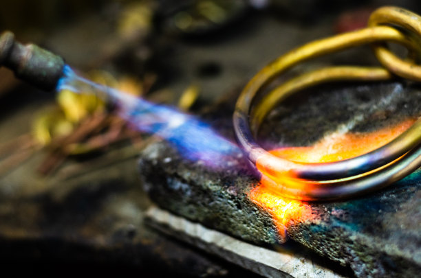 珠宝商用火焰火炬制作金手镯的特写。图片下载