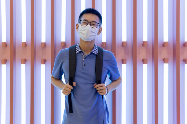 亚洲男子在霓虹灯前的面具后微笑图片下载