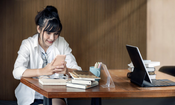 年轻美丽的女人戴着眼镜，幸福地坐在办公室里。图片下载