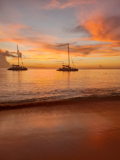 落日在巴巴多斯的海洋与帆船在地平线上包含的剪影的人图片下载