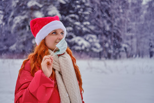 快乐女人摘下医用口罩，冬天公园里有树在雪地里图片下载