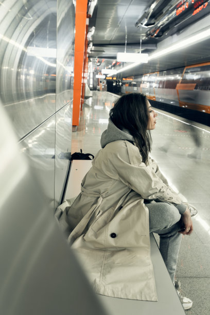 穿着米色风衣的女孩在地铁站台上等车图片下载