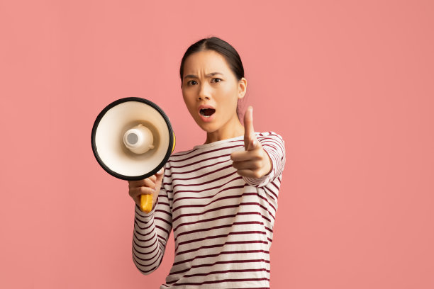 的关注。情绪化的亚洲女士拿着麦克风，手指着镜头大喊大叫图片下载
