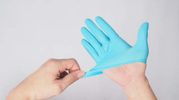 左手拉右手戴着白色背景上的蓝色乳胶手套。图片下载