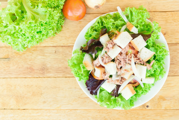 靠近金枪鱼沙拉在白色盘子上的木盘图片下载