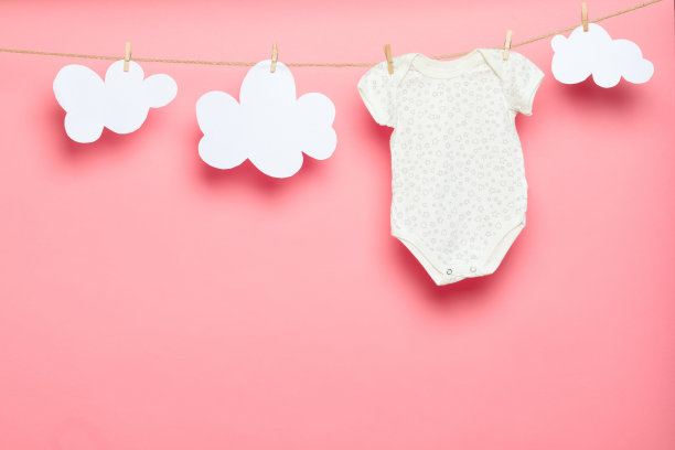 粉红色背景上晾衣绳上的婴儿衣服-图片图片下载