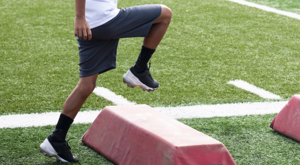 在夏季训练营中，年轻的足球运动员的下半身正在越过红色的障碍物图片下载