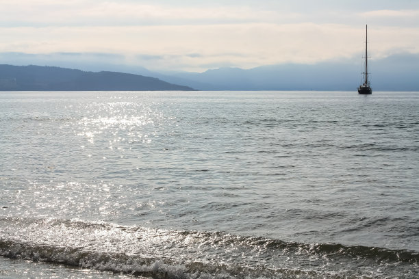 太阳在海水中的反射和帆船在地平线上的轮廓。图片下载