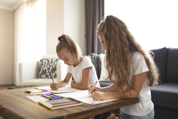 快乐的小二姐妹在家里画画。图片下载