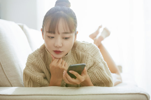 一个年轻的亚洲女人在家里操作电话图片下载