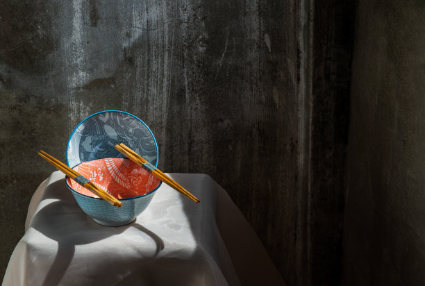 粉红色的桌布上放着两个陶瓷碗和木筷子。图片下载