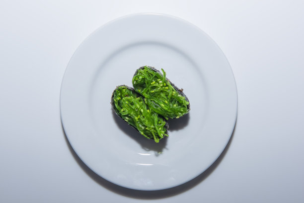 俯视图，绿色的海藻饭团放在一个圆形的盘子放在白色的桌子上。图片下载