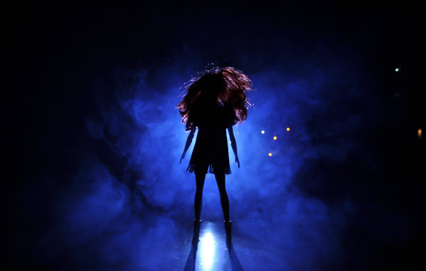 在浅色背景上的女性脸的剪影。一个长发的孤独娃娃的剪影，透过窗户的背光看到的城市风景图片下载