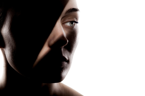 时尚工作室的可爱女孩的肖像。一个美丽的年轻女子的剪影，在白色的背景下，她的脸上有坚硬的阴影。图片下载