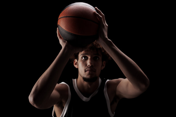 职业篮球运动员拿着球对着黑色背景。严肃专注的非裔美国人，穿着运动服图片下载