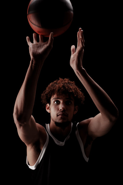 职业篮球运动员拿着球对着黑色背景。严肃专注的非裔美国人，穿着运动服图片下载