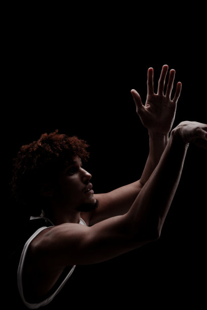 职业篮球运动员拿着球对着黑色背景。严肃专注的非裔美国人，穿着运动服图片下载