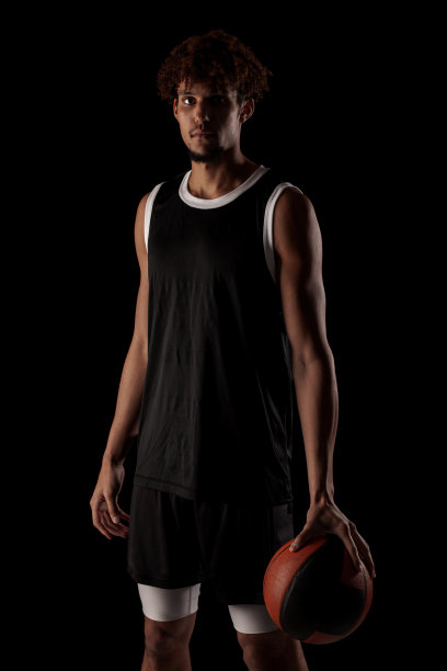职业篮球运动员拿着球对着黑色背景。严肃专注的非裔美国人，穿着运动服图片下载
