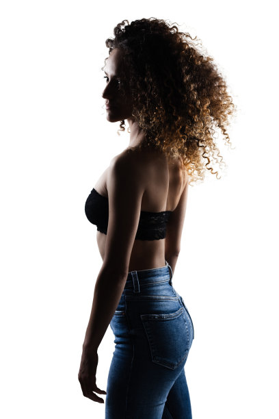 侧面照亮剪影黑发女孩与长卷发。画室人像在白色背景。图片下载