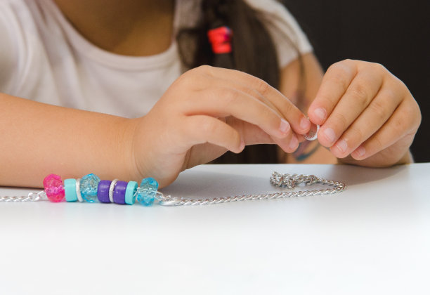 小女孩正从创意包里把蓝色和粉色的珠子串在链子上。精细运动技能，儿童发展。特写镜头。模糊的概念图片下载