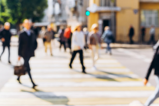 城市街道上的人们模糊了背景，在人行横道上散焦了人群过马路，在阳光明媚的户外图片下载