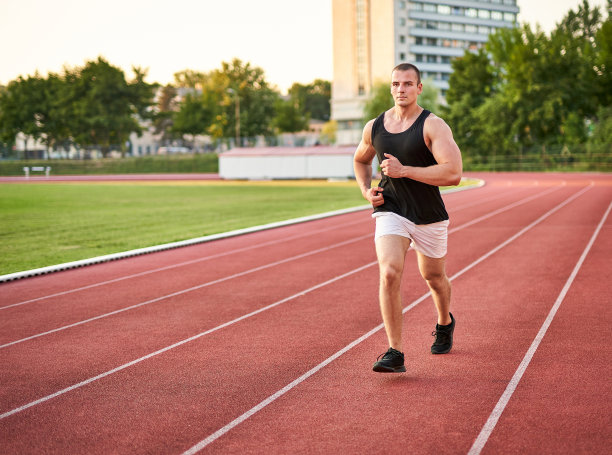 年轻健壮的男性短跑运动员在红色的跑道上跑步——与千禧一代跑步者的健身和健康概念——照片的左侧是Copyspace图片下载