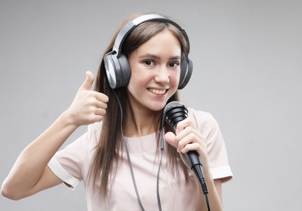 富有表现力的女孩用麦克风和耳机唱歌图片下载