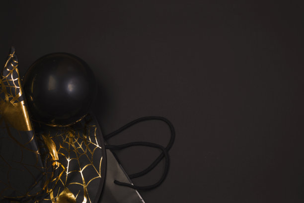 带蛛网和蜘蛛图案的黑色女巫帽，黑色背景上的派对主题球，平面放置复制空间。万圣节的节日。购物。副本的空间。图片下载