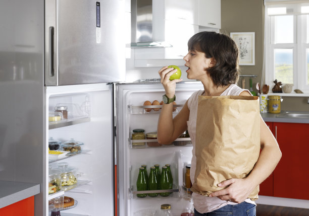 购物后整理冰箱的女人吃了苹果图片下载