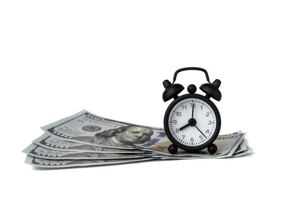 放在一百美元钞票上的迷你闹钟，时间就是金钱图片下载