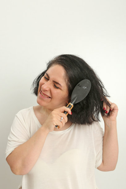 可爱的女人梳理她的头发前面的白色背景。图片下载