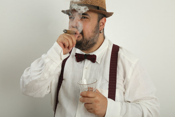 身穿亚麻衬衫、叼着雪茄、拿着威士忌的年轻男子图片下载
