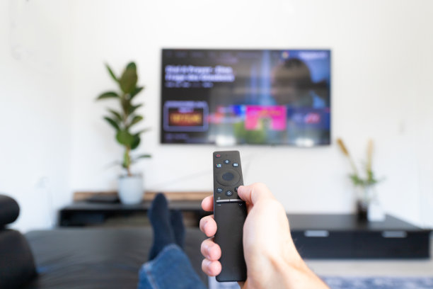 看电视和使用遥控器。用遥控器手动切换频道或打开智能电视上的应用程序图片下载